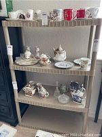 Beige three-tier plastic storage shelf with various decorative items placed on shelves for staging only.