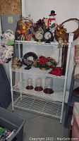Two white metal wire shelving units with various household items arranged on shelves. Shelves are empty and ready for use, made of sturdy metal wire.