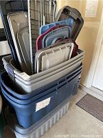 Stacked plastic storage totes with some lids resting inside and around the totes.