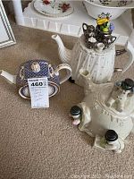 Photo shows four collectible teapots including one blue and gold Lenox teapot and three white ceramic snowman-themed teapots with black hats and snowflake details