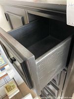 Open drawer showing interior storage depth and drawer construction with square knob.