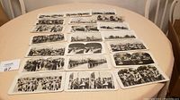 Wide shot of all 21 WW1 stereoscope view cards laid out on a round table showing various images of soldiers and military scenes.