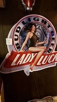 Front photo of large Bud Light Lady Luck tin advertising sign showing full design with woman holding beer bottle.