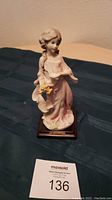 Full view of the 8-inch Guiseppi Armani girl figurine holding grapes on a dark wood base with branding plaque.