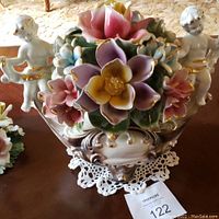 Front view showing the entire centerpiece with flowers and both cherubs holding gold ribbons.