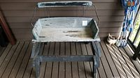Weathered antique wooden buggy bench with distressed paint, shown on a porch floor.