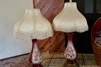 Photo of two matching vintage hand painted floral lamps with Victorian style cream fabric shades with fringe.
