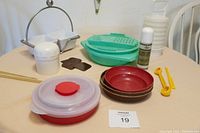 All lot items arranged on table, showing variety of vintage Tupperware and Pampered Chef pieces including serving bowls, storage containers, and kitchen tools.