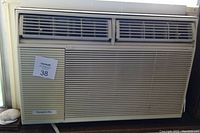 Front view of white window mounted air conditioner showing air vents and grille with Hampton Bay branding.