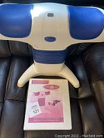 Photo showing the full Back 2 Life back-strengthening device on a dark surface with the user manual placed in front.