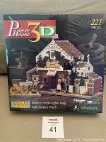 Front view of sealed Puzz 3D puzzle box showing Birdie's Perch Coffee Shop puzzle image, 221 pieces.
