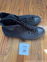 Side and top angled view of the pair of black Converse All-Star men's high-top shoes showing profile and condition.