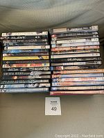 Photo of 33 DVD movies stacked in two rows showing titles and condition.