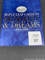 Front cover of Maple Leaf Gardens Memories & Dreams book showing title in gold on blue background and a silver circular image of the arena.