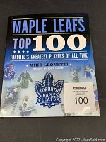 Front cover of the Maple Leafs Top 100 coffee table book showing title, author Mike Leonetti, and Toronto Maple Leafs logo with images of players.