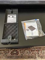 Original instruction manual and accessories in plastic sleeve placed next to the open gun case.