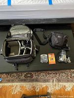 Top view of layed out items including two camera cases, Canon camera with attached lens, extra lens, and two small retail packages.