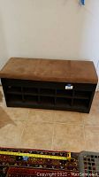 Full view of the entryway bench showing cushioned top and cubby shoe storage compartments underneath.