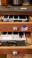 Kitchen drawer with plastic organizers containing forks, spoons, knives, and additional utensils, spoon handles and chopsticks visible