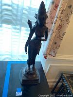 Full view of the bronze Indian woman statue showing the figure standing on a square base.