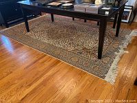 Full view of the oriental-style rug under a table on a hardwood floor showing the overall design and size.