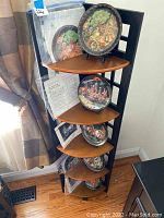 Full view of corner shelving unit displaying five decorative plates with accompanying certificates and information sheets.
