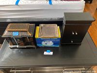 Full view of the two jewelry boxes and Sonic Wave ultrasonic cleaner on a black table, showing exterior details and size comparison.