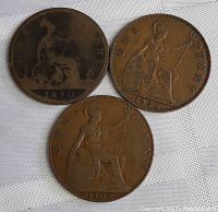 Three Canadian large pennies dated 1890, 1906, and 1936 displayed on fabric background showing frontal details.