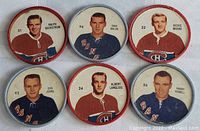 Six vintage hockey trading coins arranged in two rows of three, each with a colored rim and player photo with name and number.
