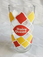 Clear vintage drinking glass featuring Dairy Queen logo with red and yellow diamond pattern around it.