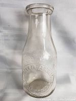 Full view of the vintage glass milk bottle showing shape and embossing