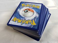 Stack of Pokémon trading cards showing backs with typical blue Poké Ball design.