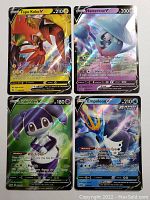 Photo showing Tapu Koko V, Hatterene V, Indeedee V, and Empoleon V holo foil cards in clear view