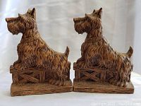 Pair of Scottie dog-shaped carved bookends with detailed textured fur, rustic finish, both facing the same direction on a white background.