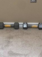 Four hexagonal dumbbells of varying weights (2, 5, 8, 10 lbs) lying on a carpeted floor.