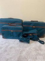 Photo of 5 piece blue and brown suitcase and bag set showing different sizes and styles of luggage placed against a wall.