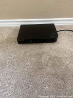 Front and top view of a black Samsung Blu-ray player with disc tray and buttons visible.