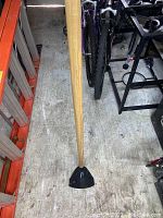 Photo of a garden hoe showing the entire tool with a wooden handle and a triangular metal blade at the bottom.