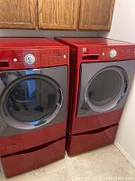 Front and side view of red Kenmore Elite washer beside matching dryer