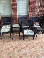 Overview of set showing 4 chairs with cushions, 2 ottomans, 2 end tables on tiled floor