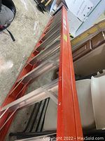 Long orange and silver A-frame ladder laid horizontally.