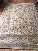Full view of the rectangular area rug showing the central Persian Garden pattern and border design in dark gold and muted floral colors.
