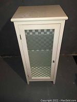 Closed front view of the white free-standing bathroom cabinet with decorative checkered glass door.