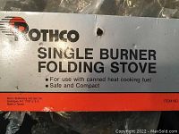 Photo of Rothco packaging label stating single burner folding stove for use with canned heat cooking fuel, emphasizing safety and compactness.