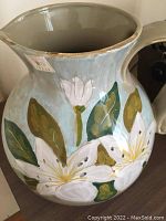 Full view of ceramic vase showing spout, handle, and floral painted design.