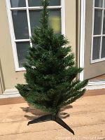 Full artificial Christmas tree standing upright revealing approximate 3 feet height and dense green pine needle branches.