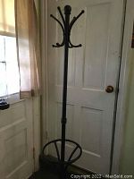 Full view of metal coat rack showing overall shape, base, and top hooks