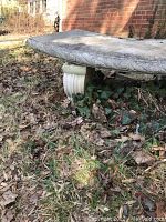 Close-up side view of a concrete garden bench showing decorative edge and rectangular leg.