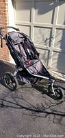 Left side view of BOB Gear jogging stroller showing black seat, canopy, and front swivel wheel.