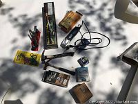 Overview of tools spread on white surface, includes boxed Hand Power Puller, measuring set box, electric tool with cord, hammer, tape measure, and small hand tools